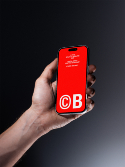 Hand holding iPhone with bright red screen displaying "CB" logo in white text