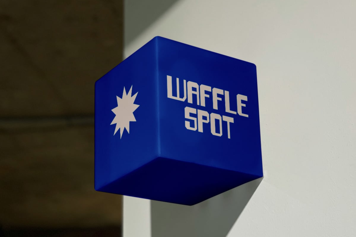 Bold blue cube signage for Waffle Spot with star burst icon on wall
