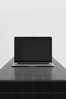 Silver laptop on dark grid table with minimal background