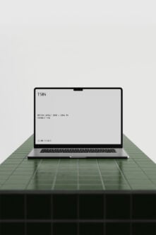 Silver MacBook on green striped table showing blank screen mockup