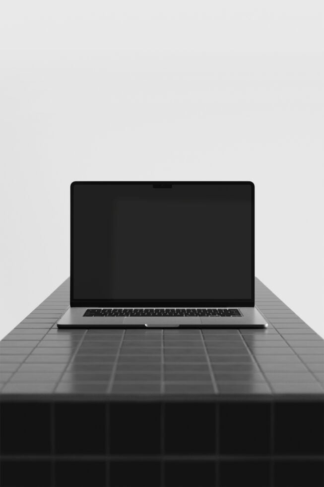 Silver laptop on dark geometric table with clean minimalist setup