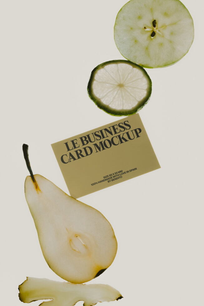 Cream business card mockup balanced between fresh fruit slices on neutral background