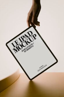 Hand holding iPad mockup with serif typography on cream background