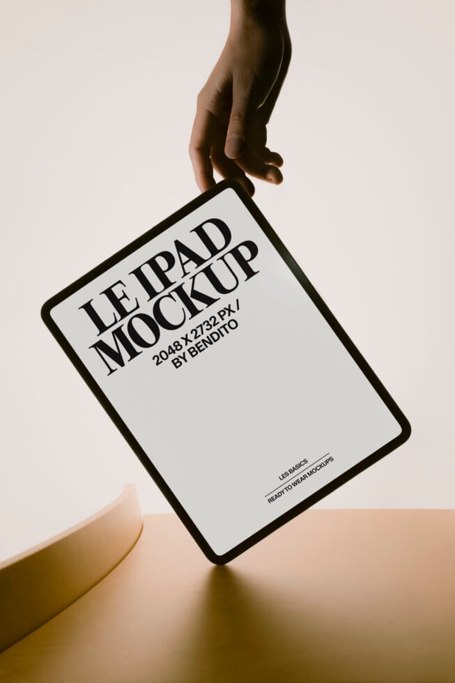 Hand holding iPad mockup with serif typography on cream background