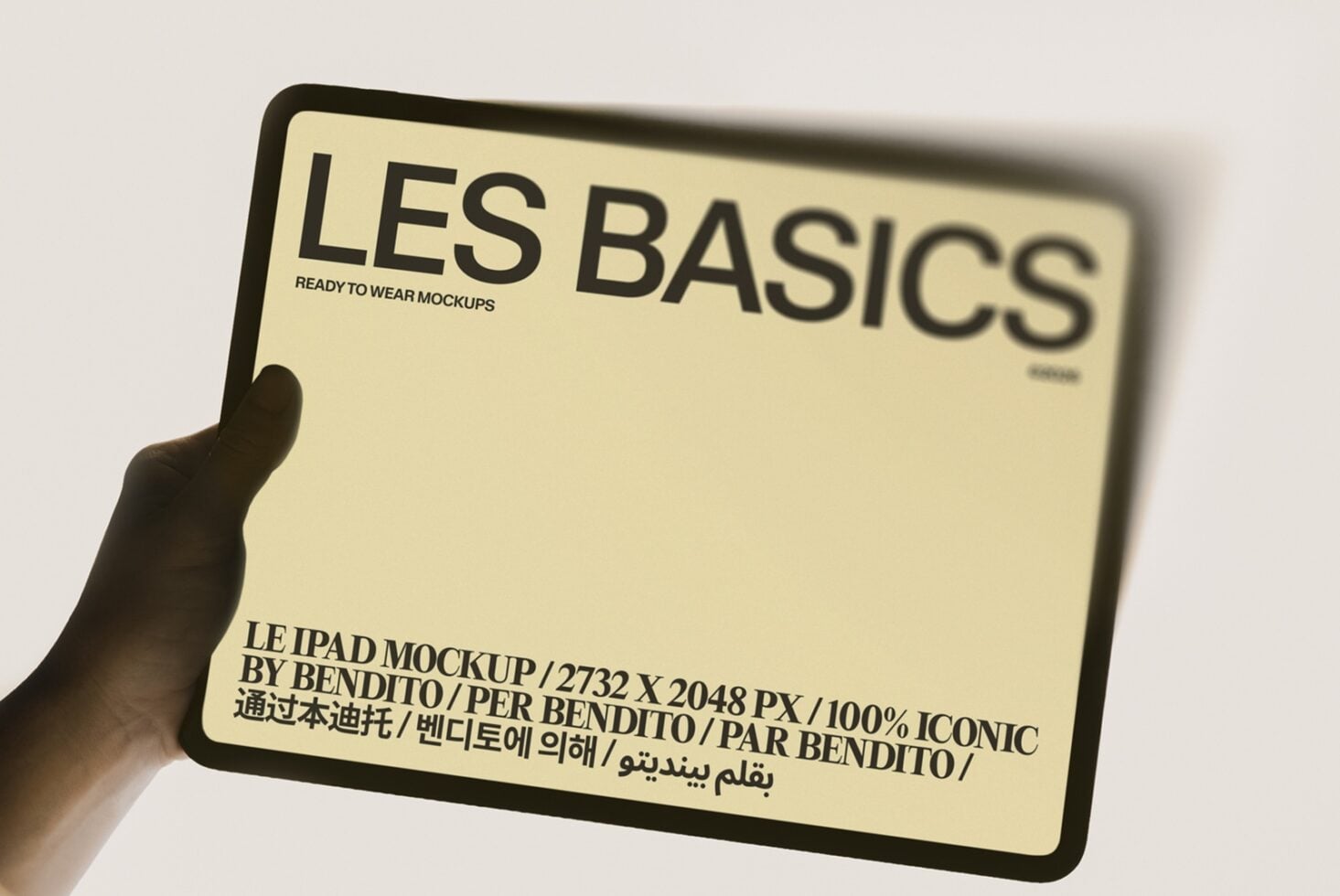 Hand holding cream iPad mockup with Les Basics branding in minimalist typography layout