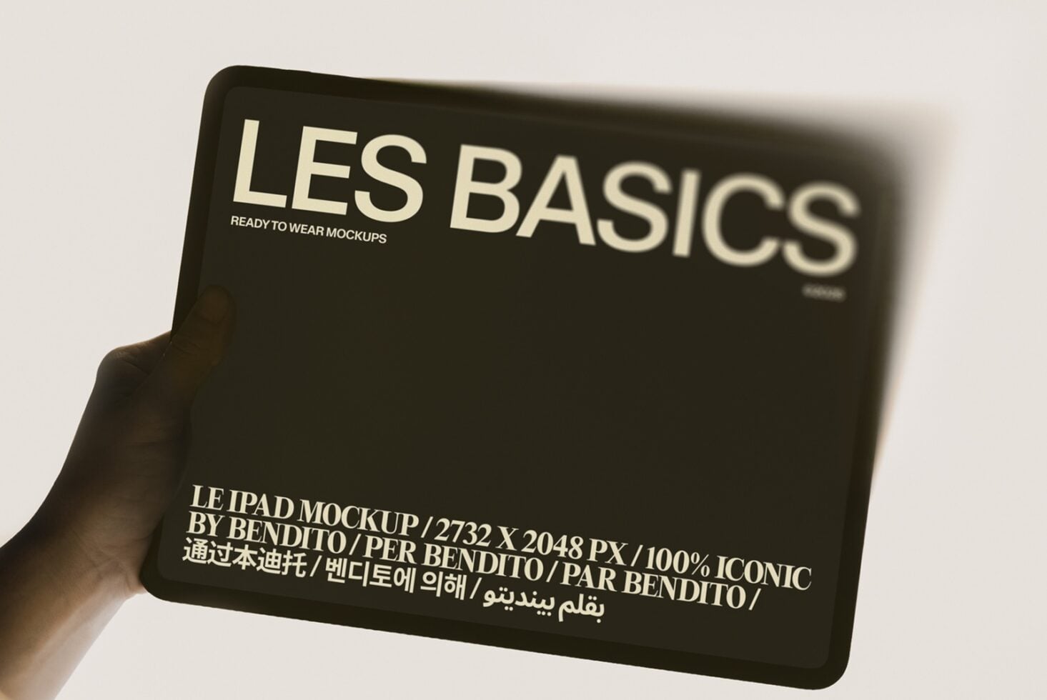 Hand holding black iPad mockup with Les Basics branding in cream text