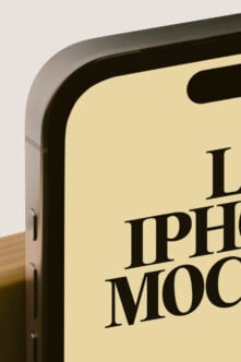 Close-up of iPhone showing cream screen with bold serif text, wooden stand visible