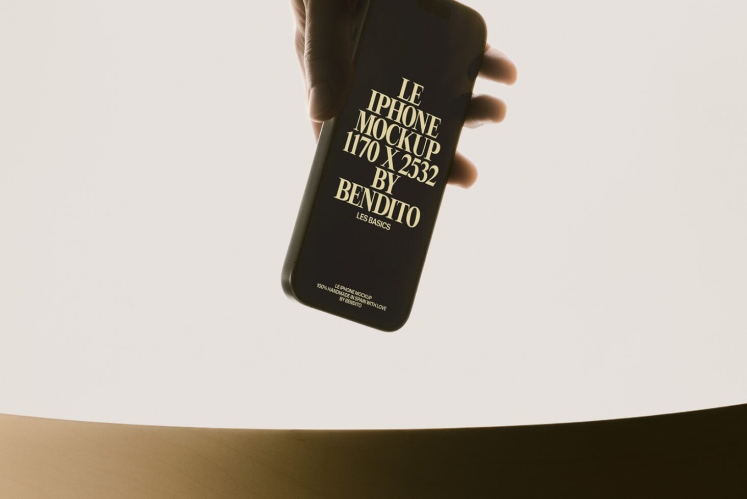 Black iPhone held in hand showing gold foil text design on cream background