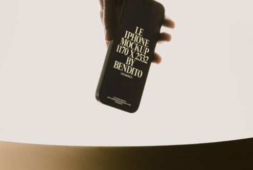Black iPhone held in hand showing gold foil text design on cream background