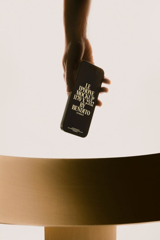 Hand holding black iPhone mockup with gold text on cream background