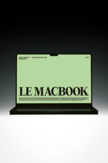 Black MacBook laptop displaying pale green screen with bold serif typography