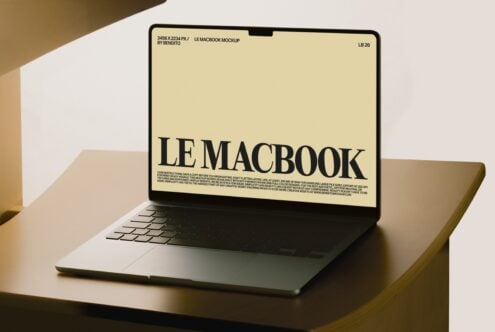 MacBook mockup with cream display showing bold serif typography on warm neutral background