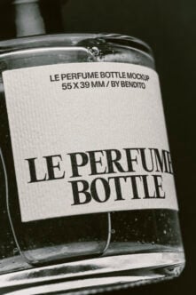 Clear glass perfume bottle with white label showing bold serif typography on dark background