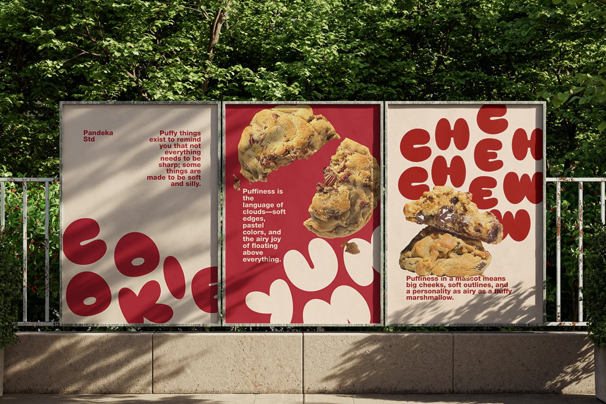 Three outdoor posters with bold red typography, cookie imagery, on cream backgrounds against green foliage