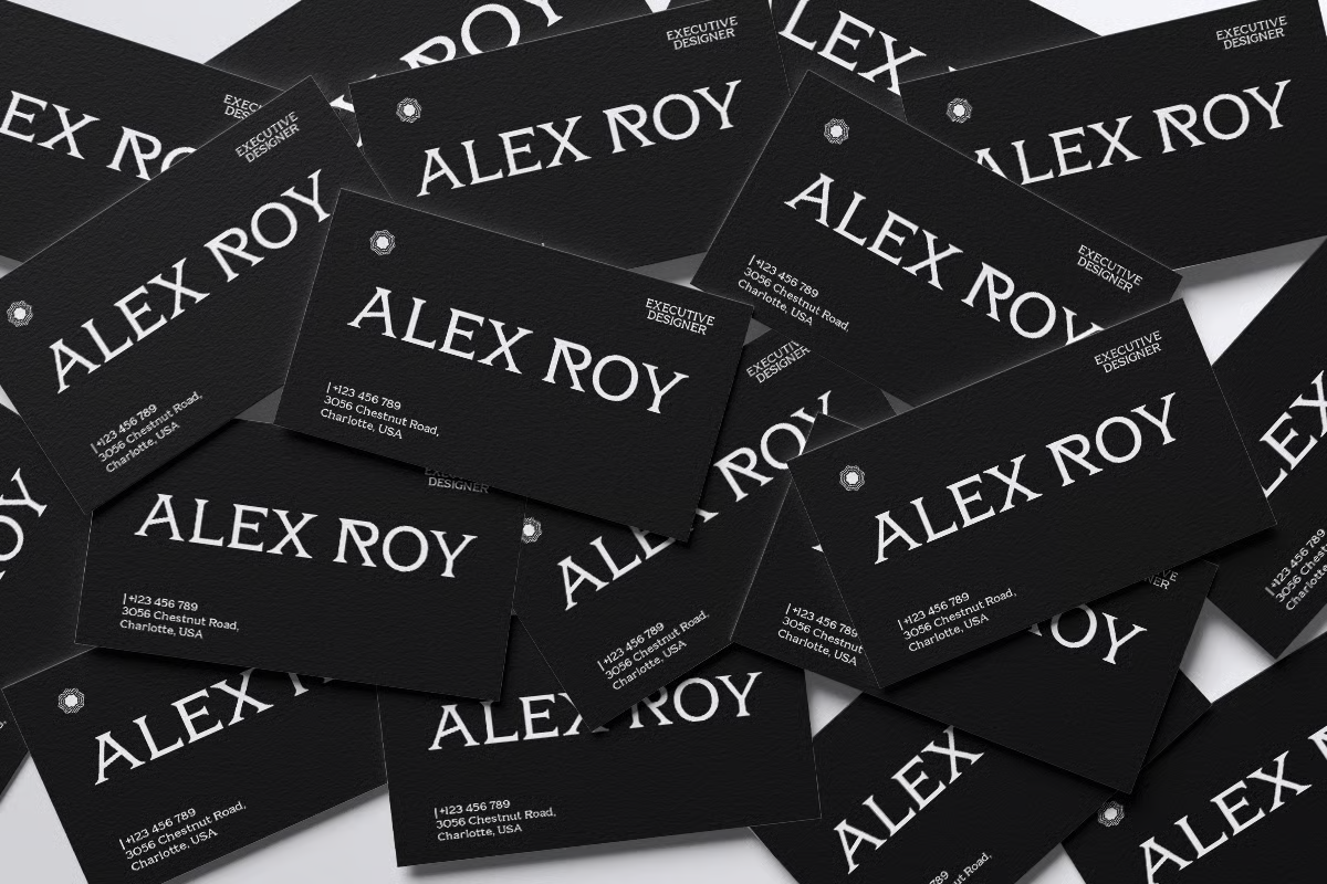 Scattered black business cards for Alex Roy, executive designer, with white serif typography, contact info, plus small metallic details