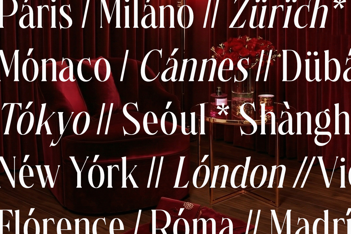 Luxury city names overlay on moody burgundy velvet chair with perfume bottles
