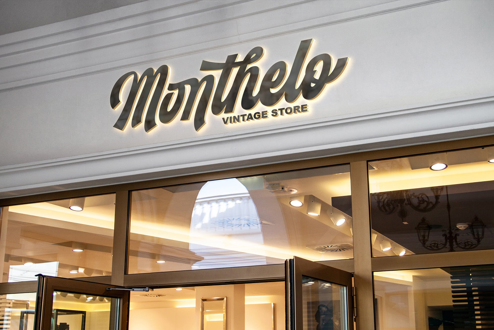Glowing gold vintage store sign with "Monthelo" script lettering on white storefront panel above glass doors