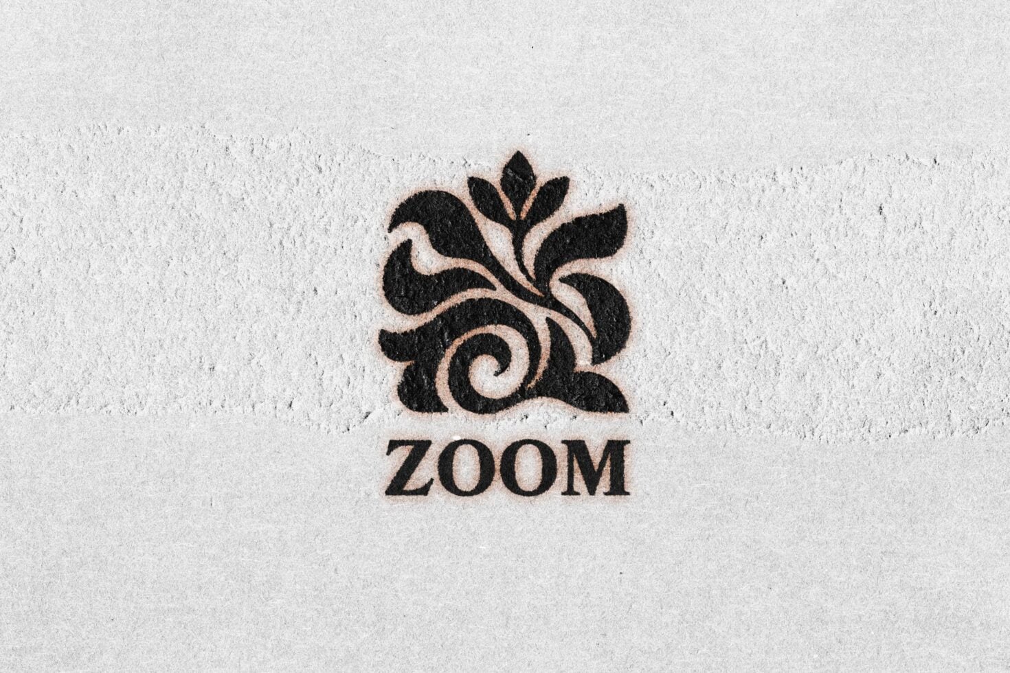 Ornamental leaf logo with swirl detail stamped on textured white paper