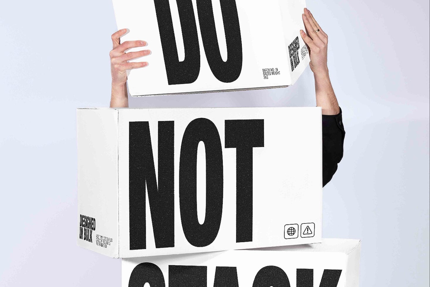 Hands holding stacked white boxes with bold black typography mockup showing shipping labels