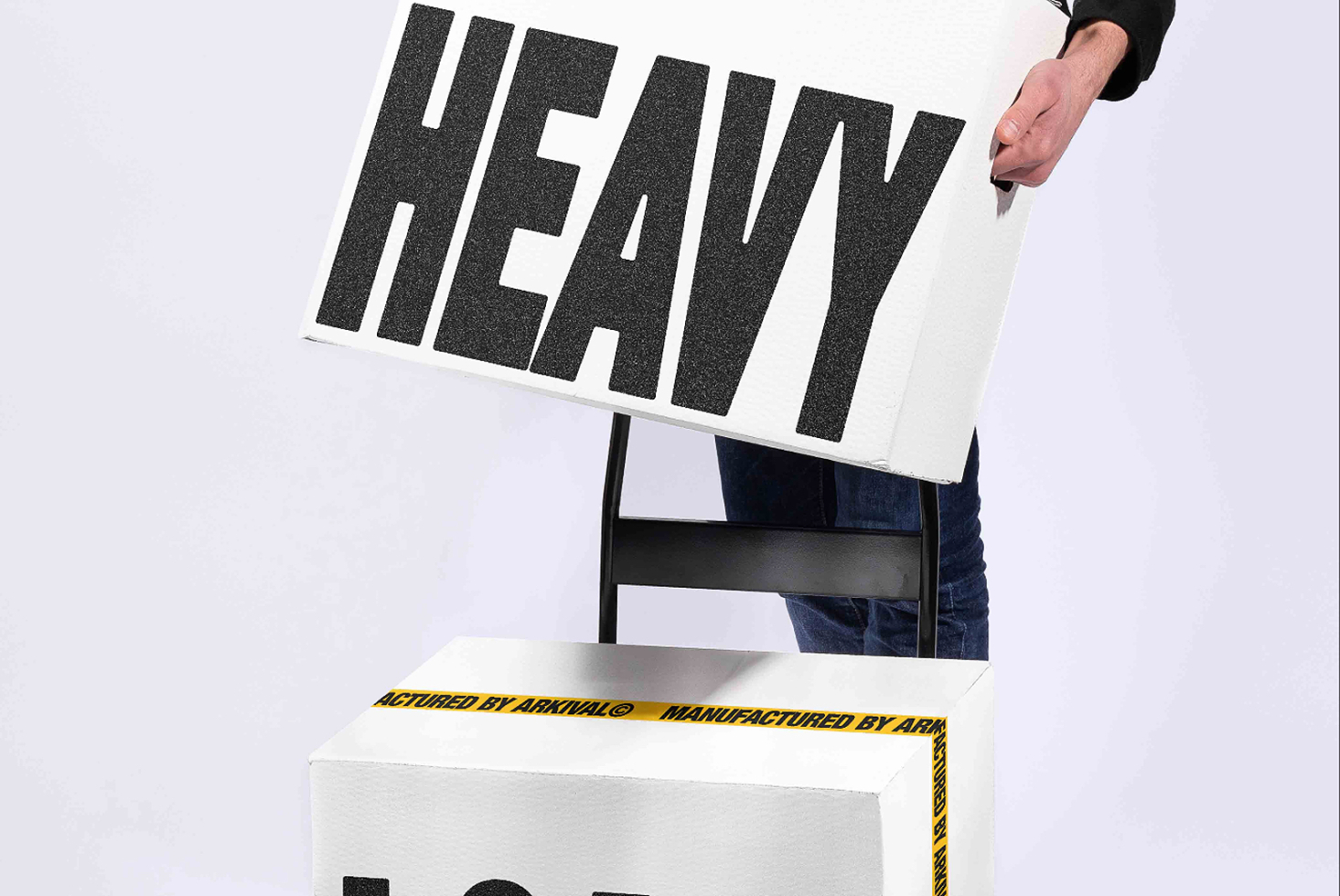 Hand holding poster mockup with heavy textured typeface over stacked boxes