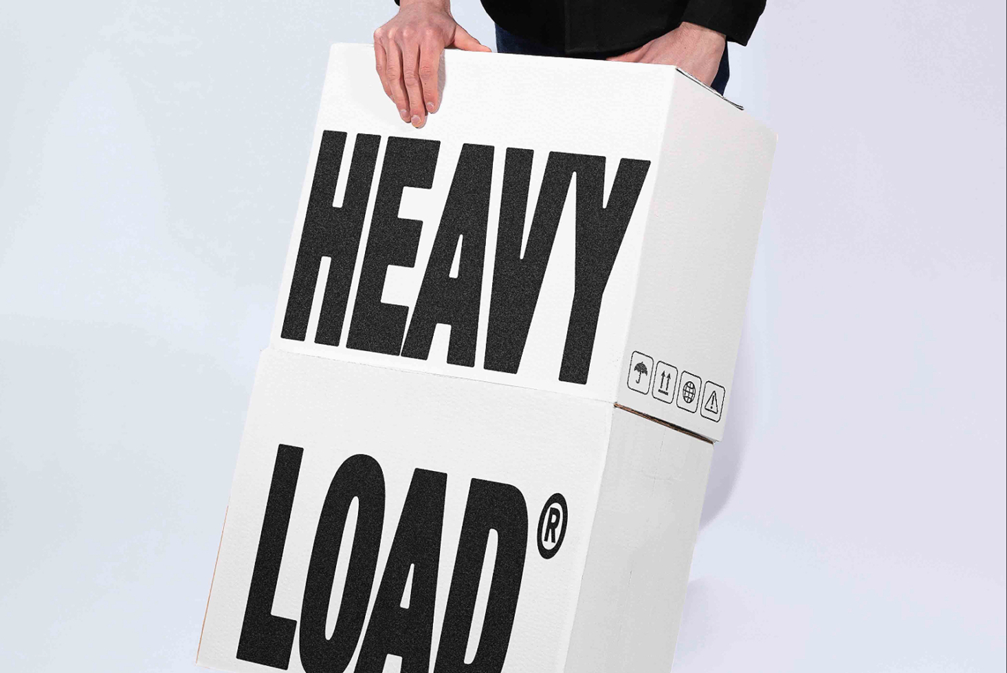 Hands holding white poster with bold black "HEAVY LOAD" typography mockup