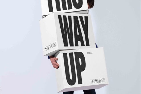 Person holding stacked white shipping boxes with bold black striped typography mockup