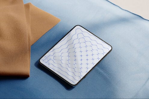 iPhone 14 mockup showing wavy line pattern on blue fabric with tan envelope nearby