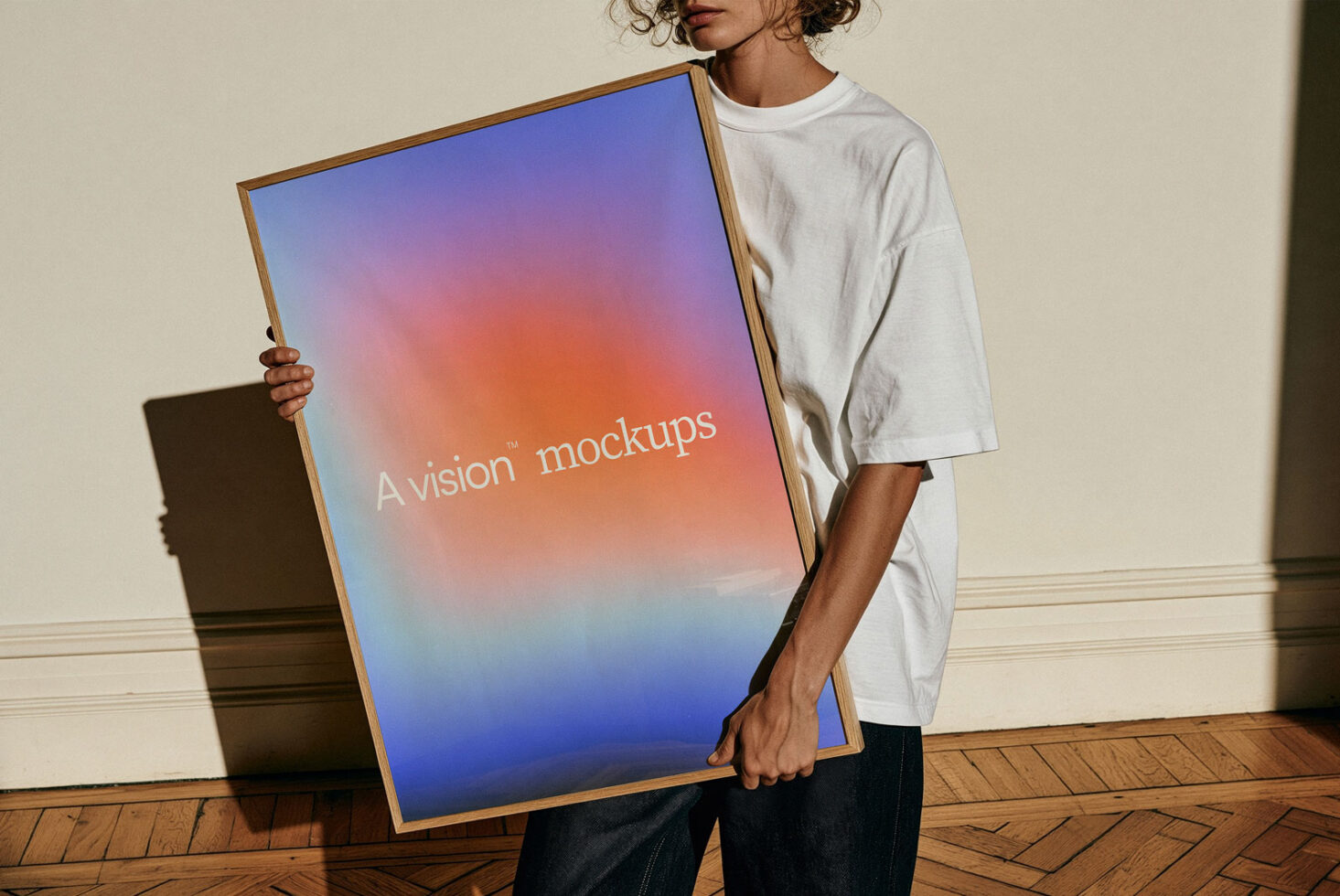 Person holding wooden-framed poster with gradient design from blue to orange in minimal room
