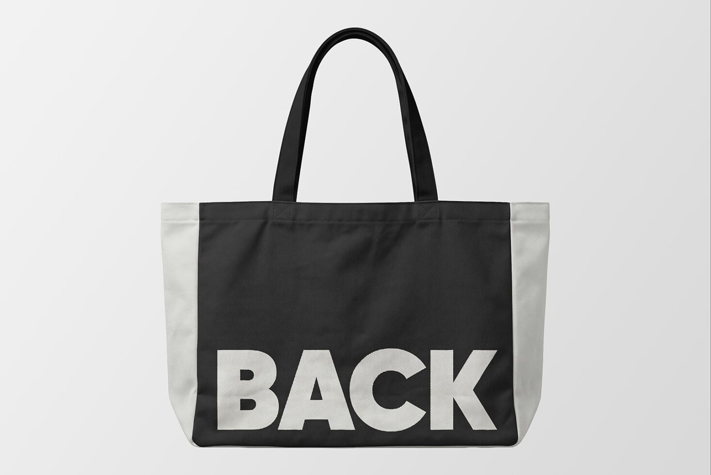 Black tote bag mockup with cream colorblock sides, bold BACK text front facing