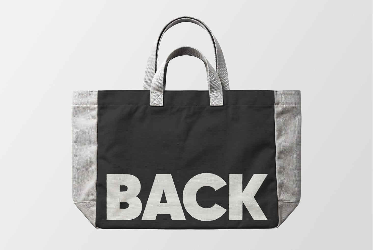 Black canvas tote bag mockup with gray handles, bold BACK text centered on front