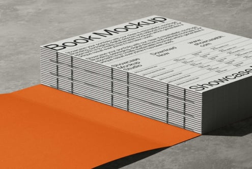 Stacked hardcover books with "Book Mockup" title on concrete floor with orange paper underneath