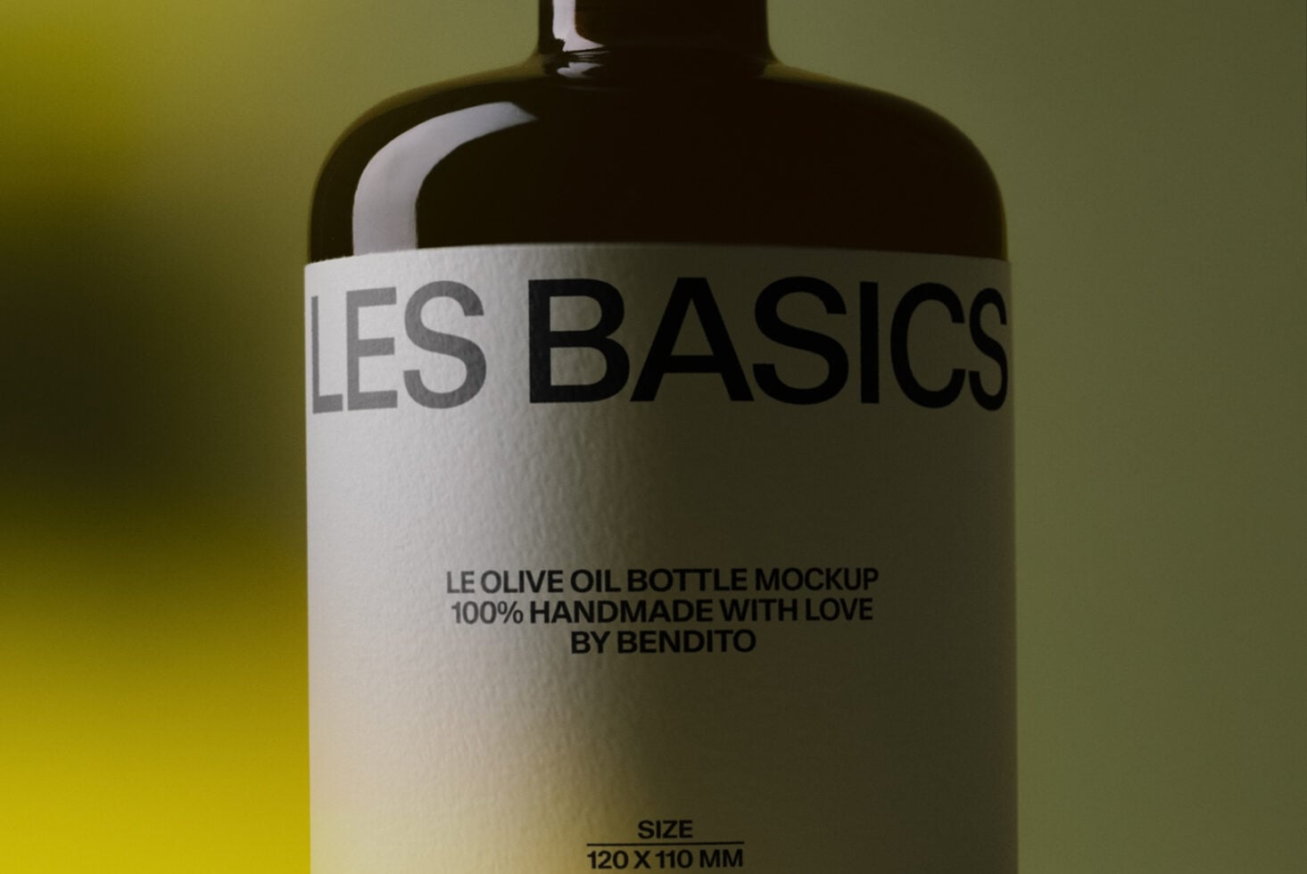 Dark glass olive oil bottle with white label showing "LES BASICS" typography on gradient yellow-green background