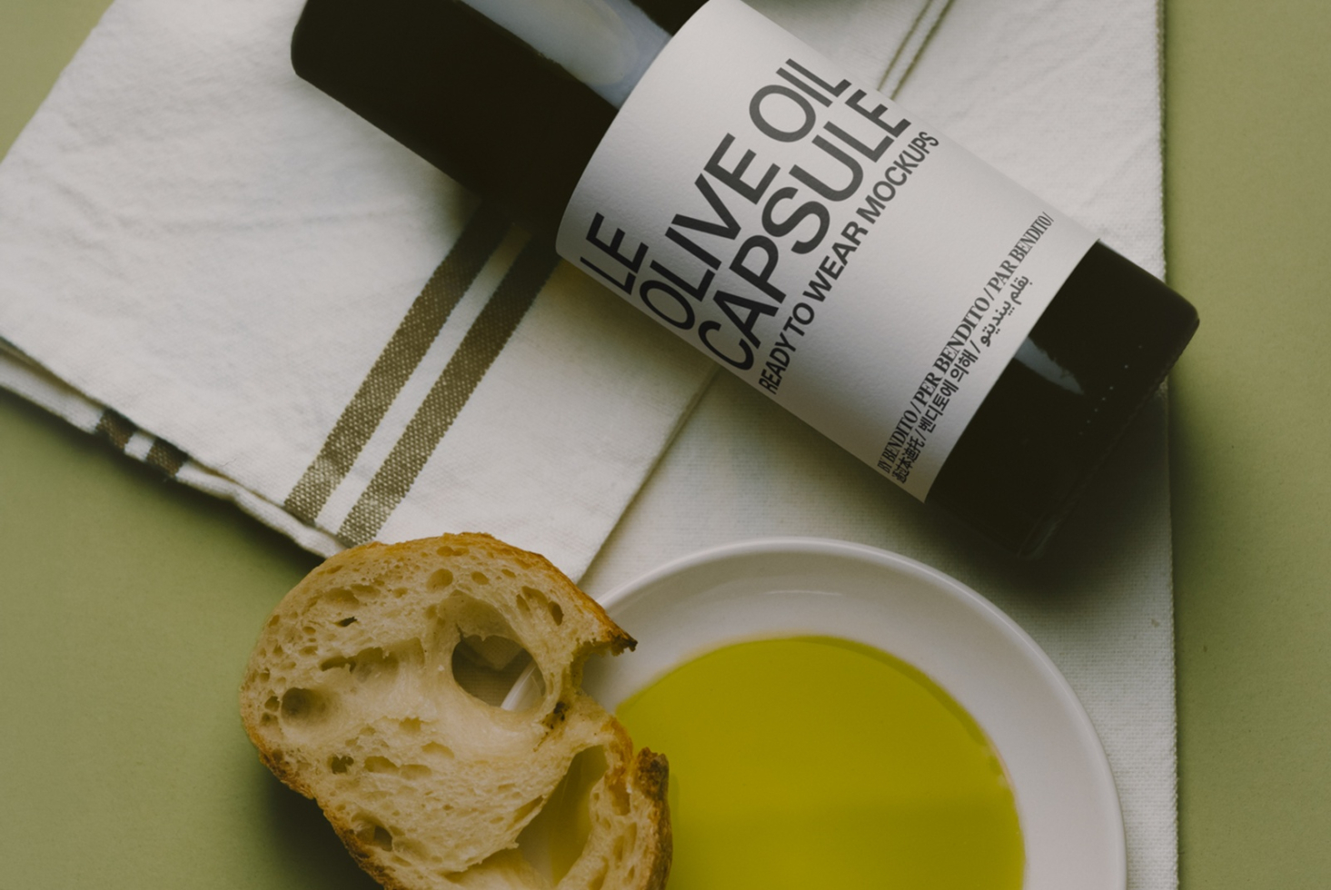 Olive oil bottle mockup styled with bread, bowl of oil, plus linen napkin on sage background