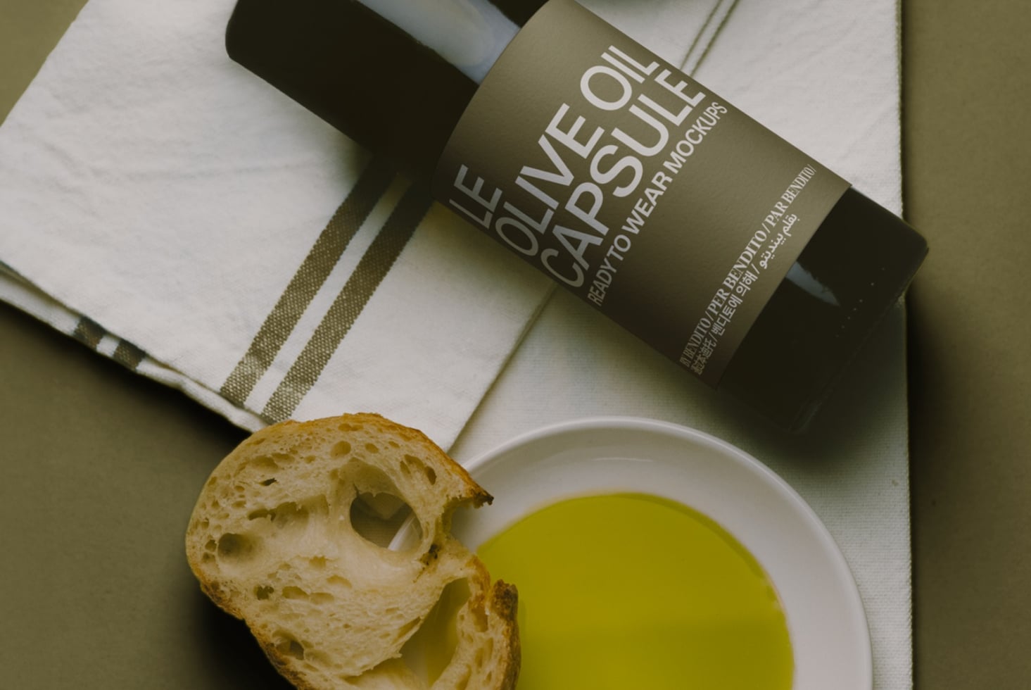 Olive oil bottle mockup with bread, bowl of oil, napkin on sage background