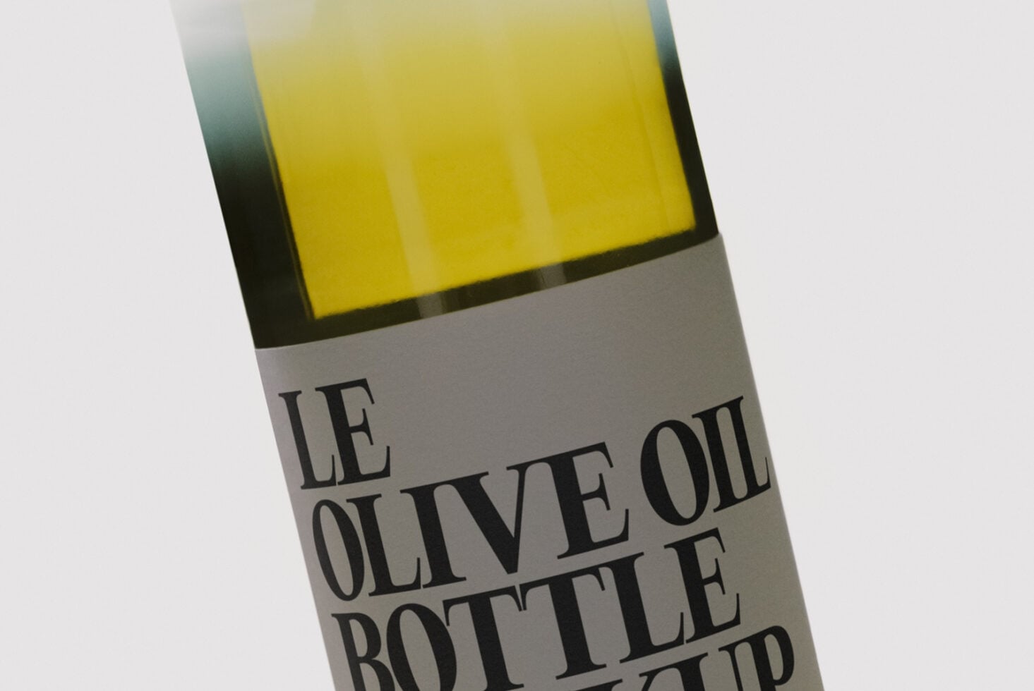 Close-up of olive oil bottle label with serif typography on cream background, yellow liquid visible above