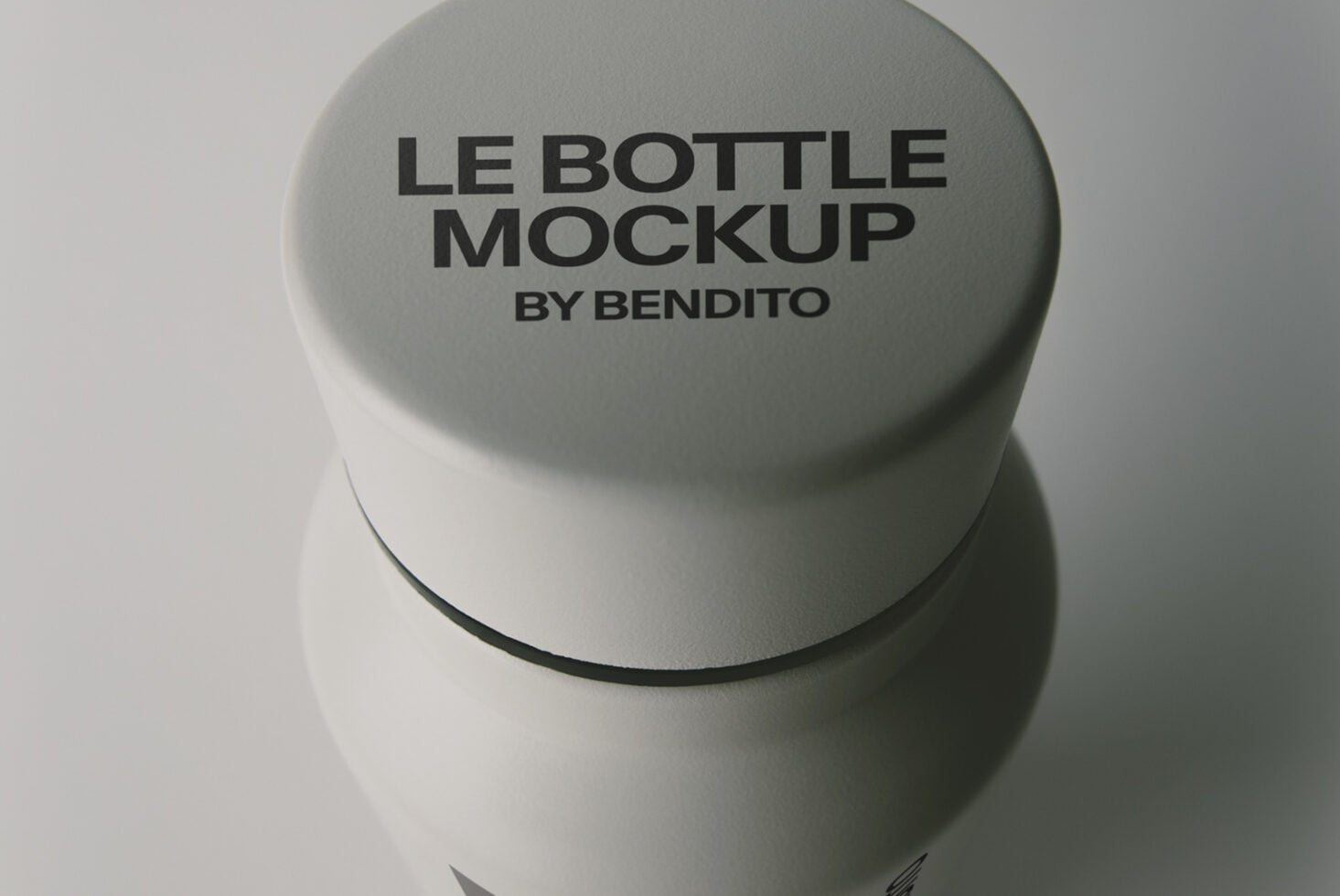 Minimal cylindrical bottle with sage green cap showing embossed text, overhead view on neutral backdrop