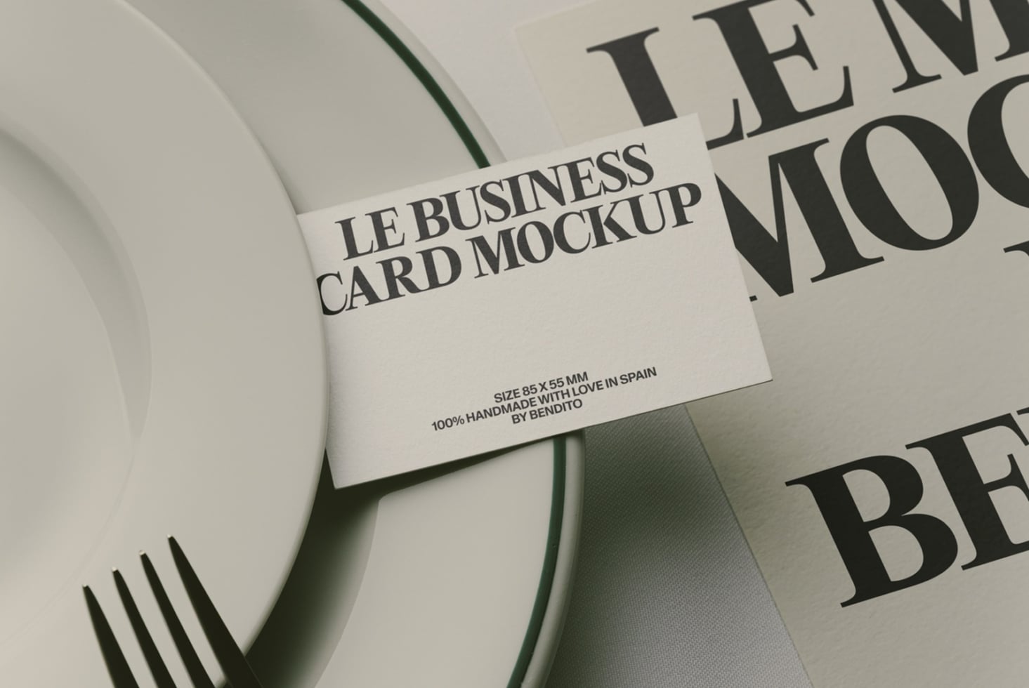 Business card mockup laying on curved white surface with magazine pages behind it