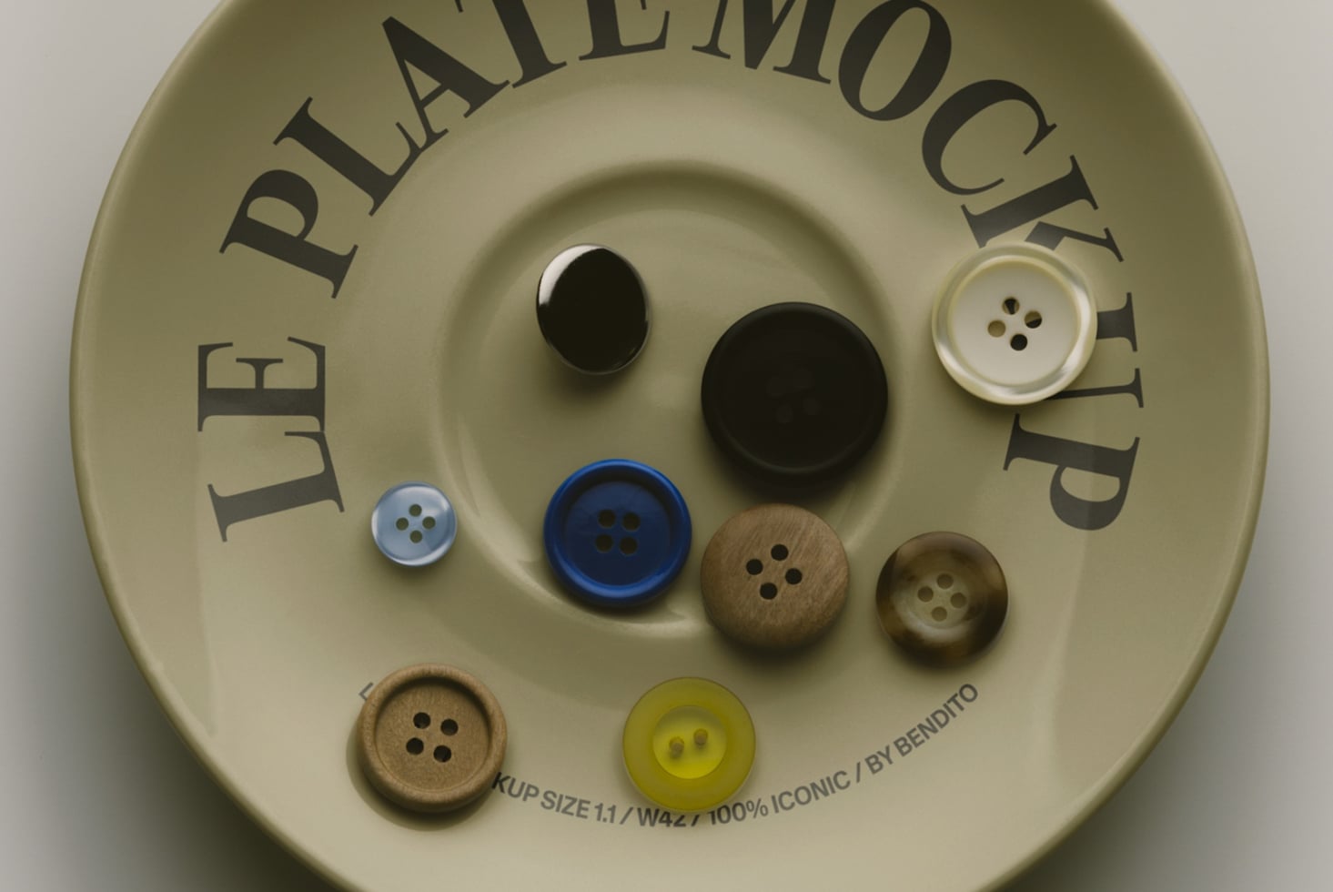 Cream circular mockup displaying various sewing buttons in black, blue, wood, pearl tones arranged on textured surface