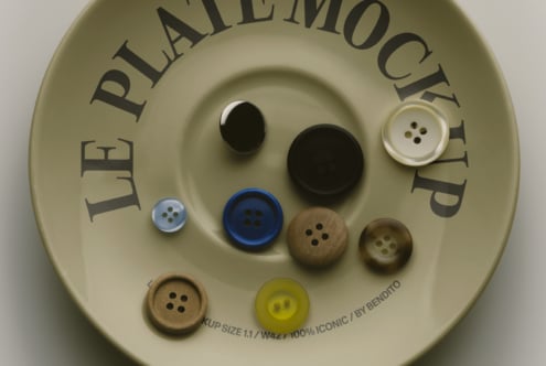 Cream circular mockup displaying various sewing buttons in black, blue, wood, pearl tones arranged on textured surface