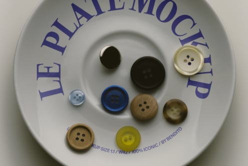 Button mockup showing various sizes in black, wood, navy, cream, plus yellow options on white plate