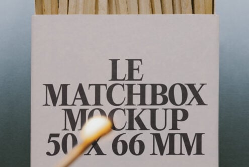 Matchbox mockup with serif typography on cream cardboard, lit match in foreground