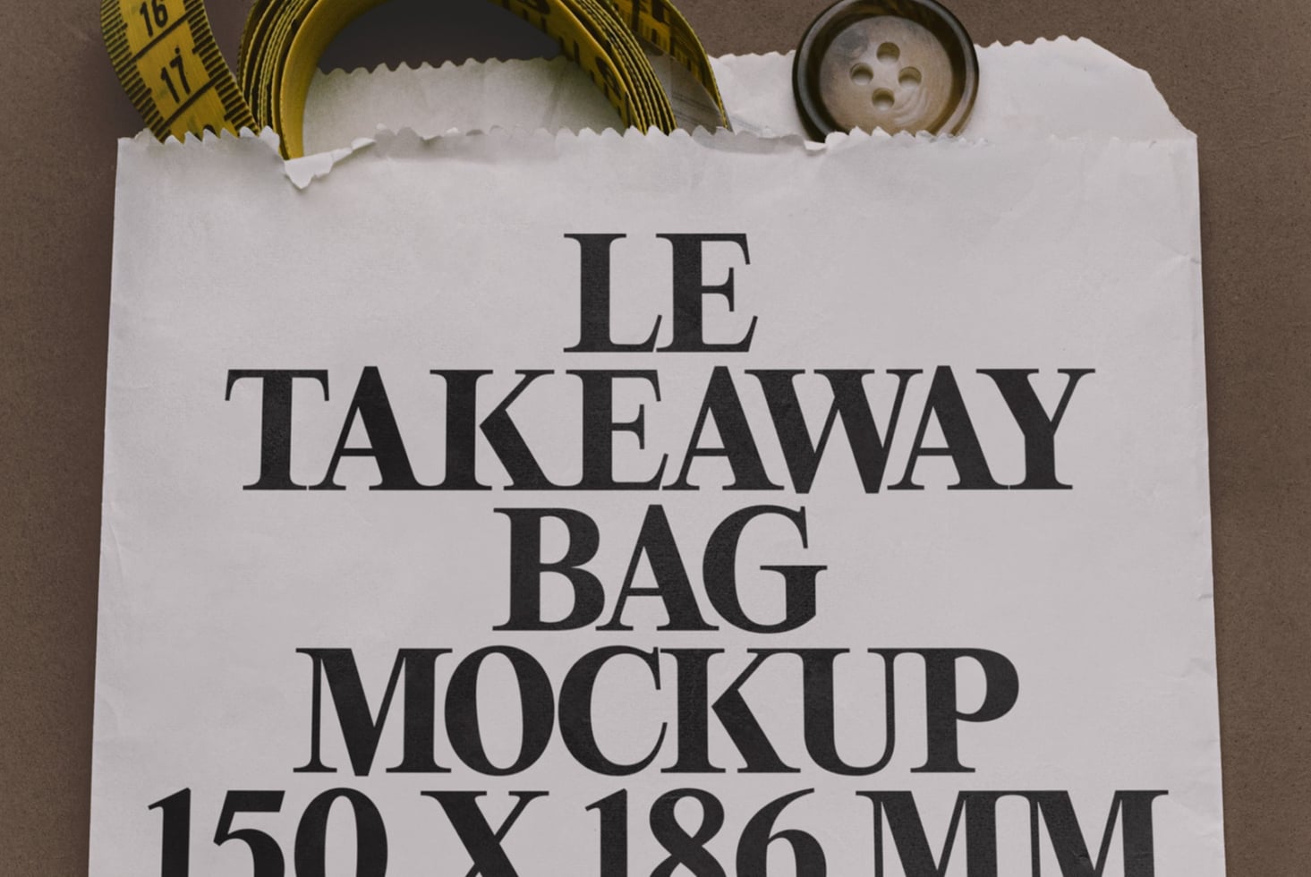 Flat lay of white paper takeaway bag with serif text, measuring tape, button, styled on brown background