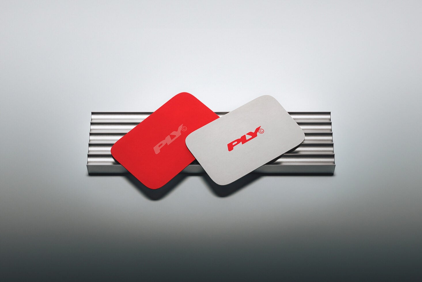 Red plus white rounded business cards leaning on metallic cylinder with soft shadows