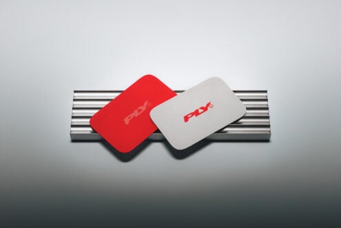 Red plus white rounded business cards leaning on metallic cylinder with soft shadows