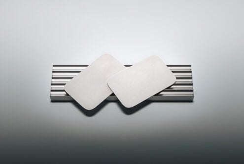 Two blank rounded square coasters on metallic striped holder with soft shadows