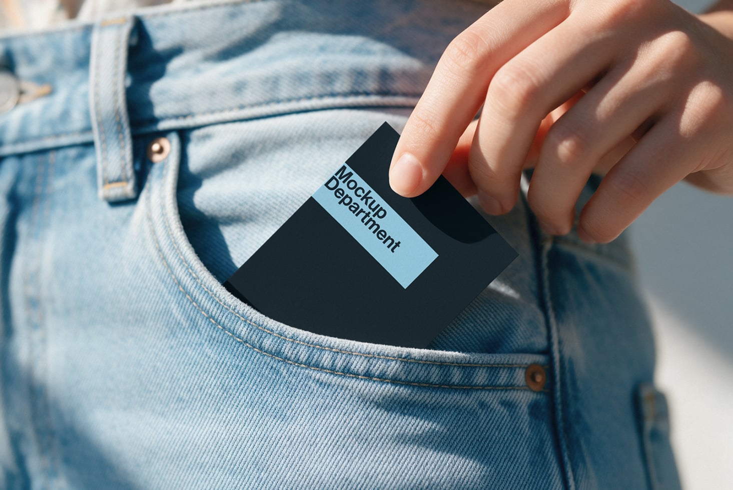 Hand pulling black box with light blue label from jeans pocket in sunlight