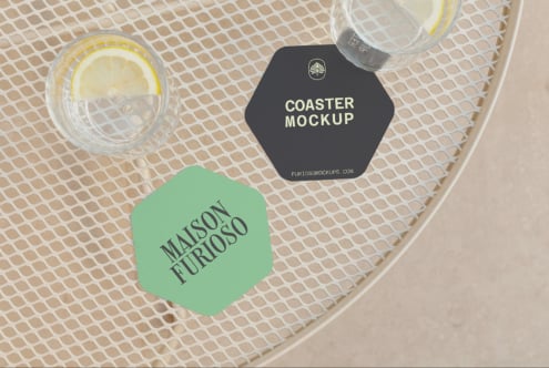 Hexagon coaster mockup with black, green labels styled on mesh surface next to lemon water