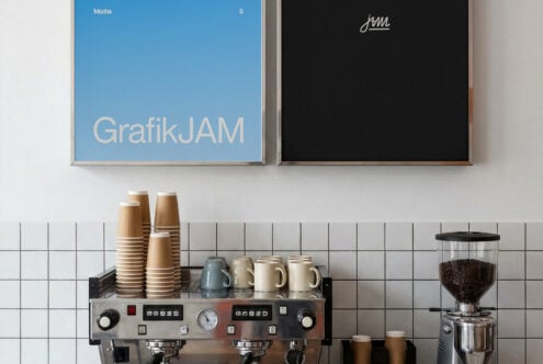 Coffee shop counter setup with espresso machine, stacked cups, grinder, plus blue poster above