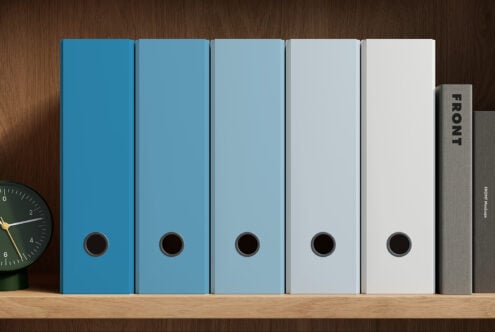 Five binder folders in gradient blue to white arranged on wooden shelf with clock
