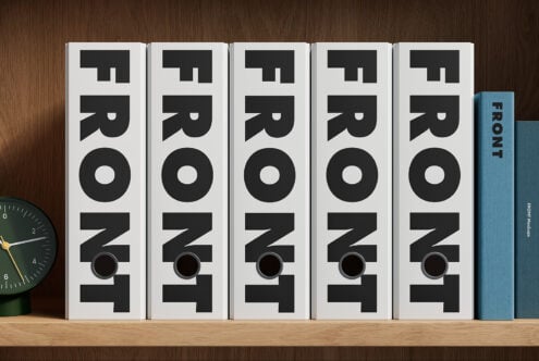 Five white books with bold black "FRONT" typography stacked on wooden shelf next to blue book